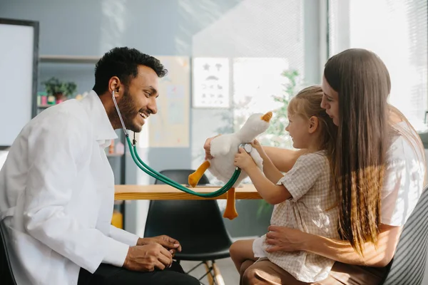 小児科医は 子供との接触 良好な関係を確立する 幸せな少女 おもちゃとスタスコープで楽しいゲームをする母親と家族の医師 — ストック写真