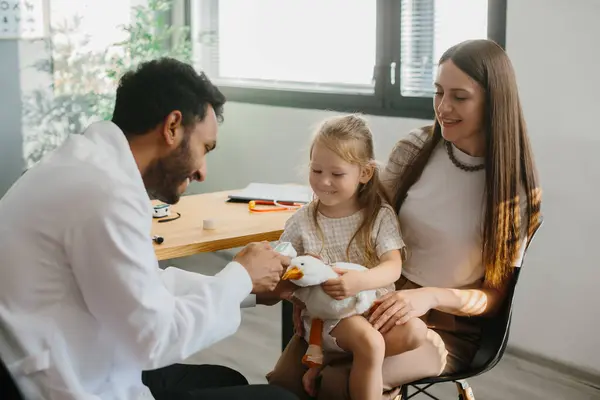 Doktor, çocuk hastayla temas kurmak ve güvence altına almak için oynar..
