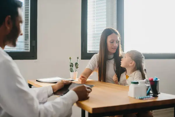 タブレットを手に入れた若い小児科医が 娘と母親に相談する 子供の医師の任命の概念 — ストック写真