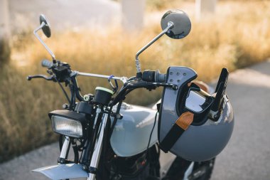 Gözlüklü bir motosikletçinin miğferi bir kafe yarışçısının sapına asılı..