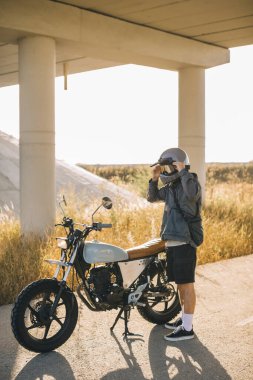 Motosikletli adam şehir dışında yolda, gün batımında..