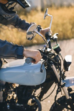 Günbatımında otoyolda klasik motosikletli bir adam. Bir adam kafe yarışçısı sürüyor. Bisikletçi yaşam tarzı konsepti