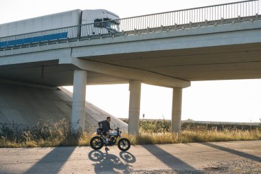 Günbatımında kavşakta, otoyolda şık bir kafede genç bir motorcu..
