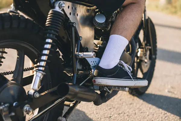 Close-up of a biker\'s leg on a motorcycle stand.
