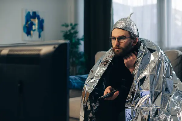 Young Man Wearing Tinfoil Hat Wrapped Tinfoil Blanket Sitting Couch — Stock Photo, Image