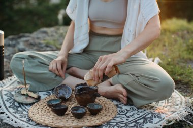 Gün batımında dağlarda çay seremonisi. Genç bir kadın doğada meditasyon yapar.