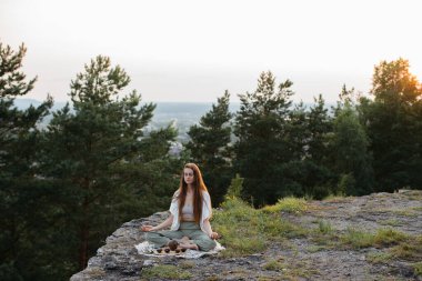 Gün batımında dağlarda çay seremonisi. Genç bir kadın doğada meditasyon yapar.