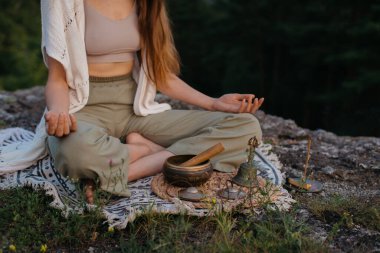 Genç ve güzel bir esmer kadın, batan güneşin ışınlarında, bir çam ormanının arka planında meditasyon yapıyor..