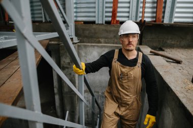 Bir inşaat mühendisi tahıl ambarının inşaat alanında metal bir merdivene tırmanır..