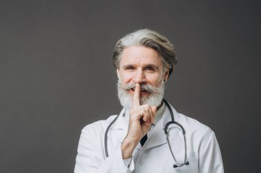 Beyaz önlüklü, gri saçlı erkek doktor. Gri arka planda izole edilmiş. El ele, el ele.