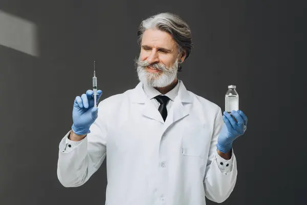 Šedovlasý Starší Lékař Bílém Plášti Držící Injekční Stříkačku Lahvičku Injekcí — Stock fotografie