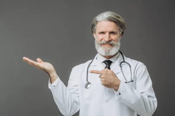 Ein Grauhaariger Arzt Weißen Arztkittel Zeigt Einen Leeren Raum Stockfoto