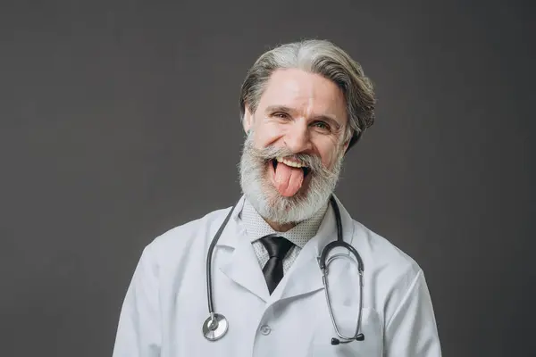 Ältere Männliche Arzt Zeigt Seine Zunge Blick Die Kamera Stockbild