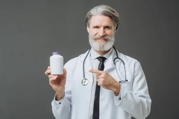 Ein Grauhaariger Arzt Weißen Arztkittel Zeigt Der Kamera Eine Flasche Stockbild
