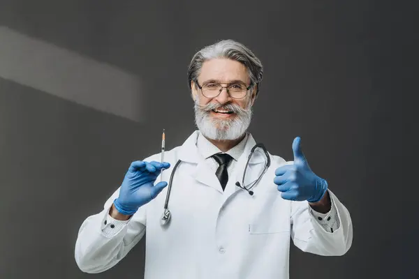 Medico Anziano Con Capelli Grigi Tiene Una Siringa Pollice Sorridendo Fotografia Stock