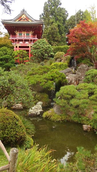 Japon tapınağı, ağaçlarla çevrili, Bonsai ağaçlarıyla çevrili bir gölette sona eren şelalenin yanında, huzur ve sükunet hissi veren.