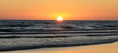 Palmar sahilindeki dalgalara yansıyan portakal rengi günbatımı güneşi İspanya