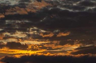 Gün batımında sıcak ışıkla aydınlanan katmanlı kara bulutlar. Karamsar ve dramatik bir akşam gökyüzü doğal arka plan ya da atmosfer sahneleri için mükemmel.