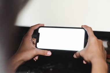 Siyah cep telefonunu boş ekran ile tutan kadınların ellerinin görüntüsü.