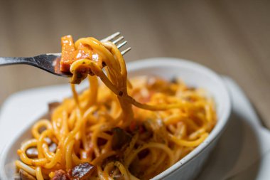 Geleneksel makarna beyaz tabakta, tahta masa arkasında.