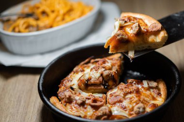 Koyu ahşap arka planda küçük bir pizza.