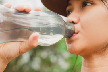 Kadın koşucu sokakta su içiyor.