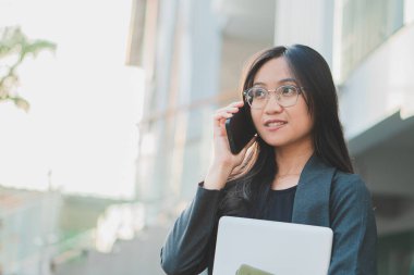 Kendine güvenen iş kadını cep telefonu kullanıyor ve internette çalışıyor.