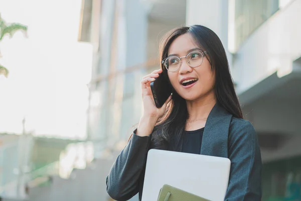 Kendine güvenen iş kadını cep telefonu kullanıyor ve internette çalışıyor.