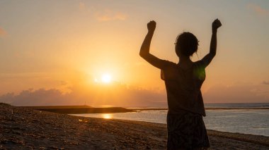young woman in the sea at sunset