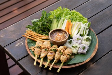 shrimp fried noodles on a plate with sauce, fried rice, vegetables and sauce on wooden table