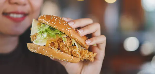 Hamburger tutan kadınların ellerini kapatın.