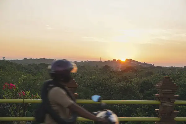 Sırt çantalı motosikletli bir adam dağların arkasında ve günbatımında