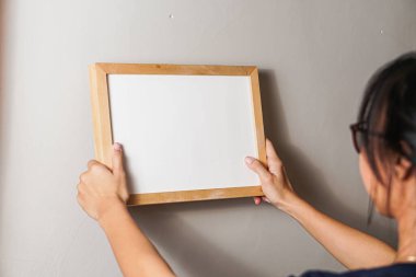 metin için beyaz boş duvar ile çerçeveyi tutan kadın el.