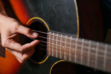 close up of acoustic guitar with a strings of a man