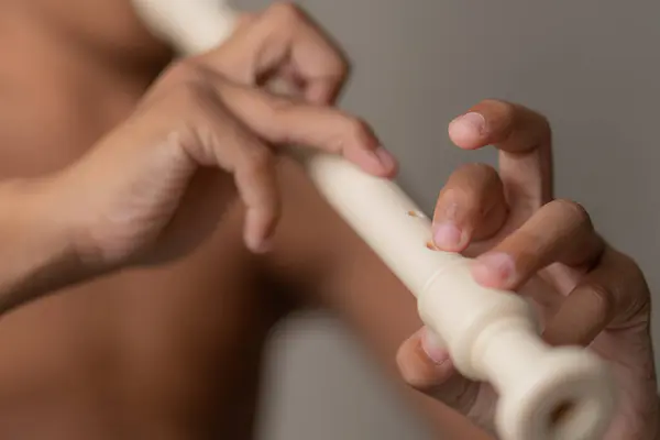 close up of a man 's hands playing with a wooden flute