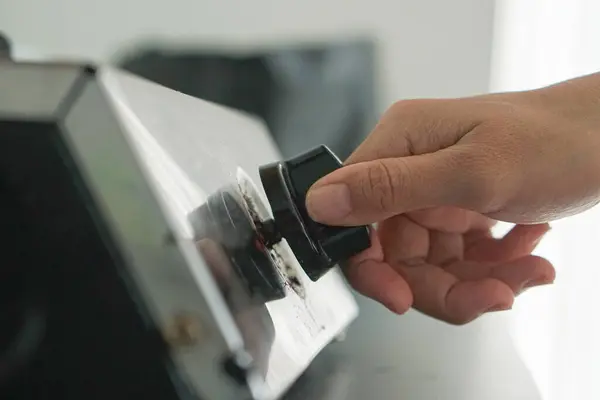 hand putting black button on the button of the machine