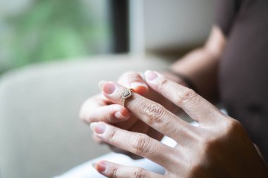 Parmağına elmas yüzük takan birinin yakın plan fotoğrafı. Geçmişi bulanık..