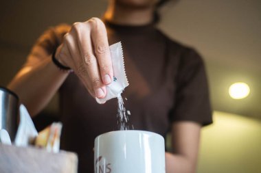 Paketten bir fincan kahveye şeker döken birini yakından çek..