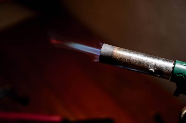 Koyu bir arkaplanda mavi bir alevle yanan bir kaynak makinesinin yakın çekimi.