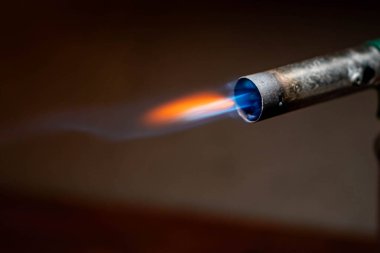 Mavi ve turuncu bir alevle kaynak makinesinin yakın çekimi.