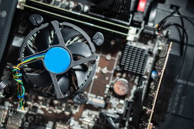 Soğutma vantilatörü, çeşitli elektronik parçaları ve kabloları olan bir bilgisayar anakartının yakın görüntüsü..