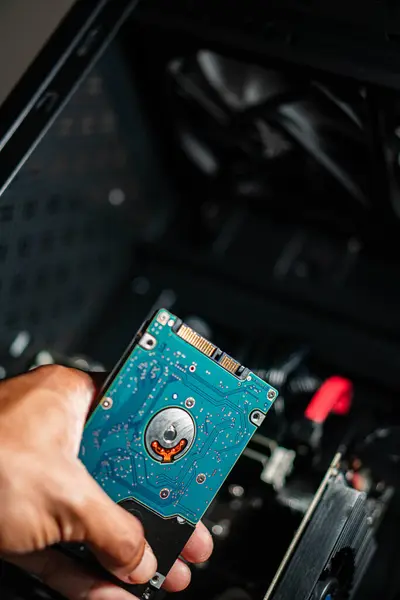 Bilgisayar çantasının yanında mavi bir sabit disk tutan bir kişi..