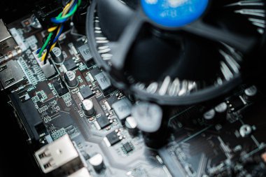 Çeşitli elektronik parçaları ve soğutma vantilatörü olan bir bilgisayar ana kartının yakın görüntüsü.