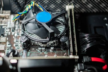 Soğutma vantilatörü ve çeşitli elektronik bileşenleri olan bir bilgisayar ana kartının yakın görüntüsü.