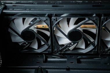 Bilgisayar soğutma vantilatörlerini bir bilgisayar kabının içinde, beyaz bıçaklı ve siyah çerçeveli üç vantilatörü gösteriyor..