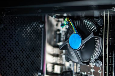 Masaüstü çantasının içinde mavi vantilatörü olan bir bilgisayar işlemcisinin yakın görüntüsü. Görüntü bir bilgisayarın iç bileşenlerini gösteriyor, ana kart ve soğutma sistemi de dahil..