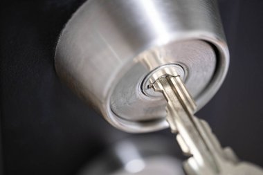 Anahtar ve kilit mekanizmasına odaklanarak bir kapı kilidine yerleştirilmiş bir anahtarın yakın plan görüntüsü.