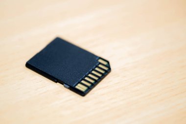 Tahta bir yüzeye yerleştirilmiş siyah bir SD kartın yakın çekimi..