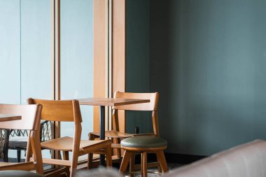 Ahşap sandalyeleri, masaları ve deniz mavisi duvarları olan minimalist bir kafe..