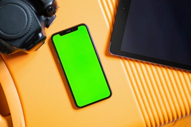 Yeşil ekranlı akıllı bir telefon ve turuncu desenli bir tablet..